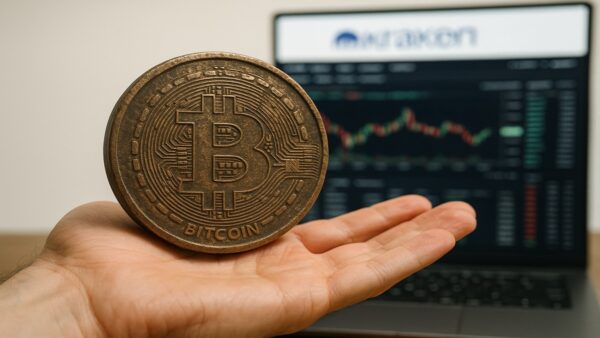 Une photo conceptuelle d'une main tenant une très vieille pièce de Bitcoin (BTC), symbolisant la vente des 11 000 BTC d'Owen Gunden après 14 ans de HODL, transférés vers Kraken en novembre 2025.