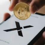 Une photo conceptuelle montrant le logo X (Twitter) sur un téléphone et une pièce de Dogecoin (DOGE), symbolisant le projet "X Money" d'Elon Musk pour les paiements crypto en 2025.