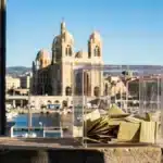 Urne électorale symbolisant les enjeux décisifs du premier tour des élections municipales à Marseille, avec Notre-Dame de la Garde en fond.