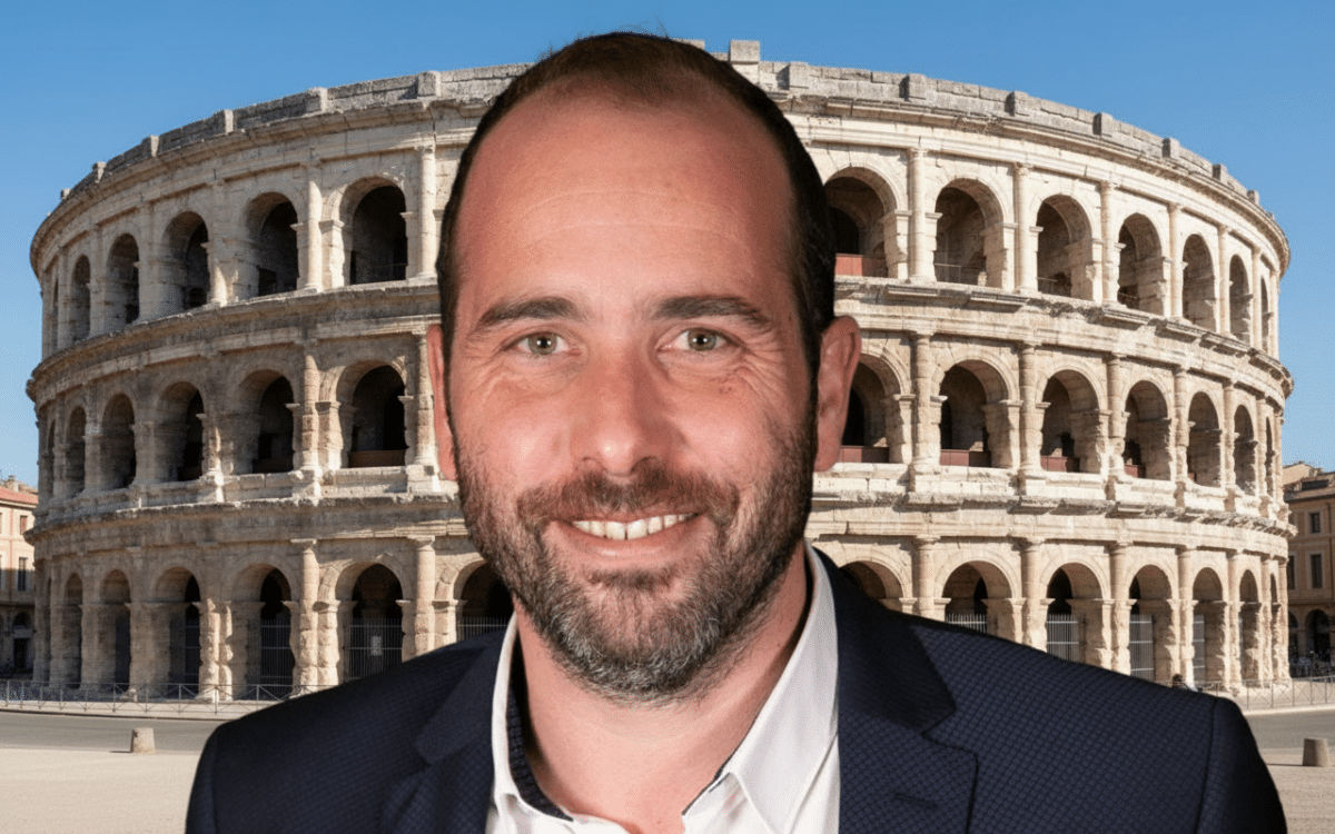 Projection en plein air du documentaire participatif "Si je vous dis Nîmes" dans un quartier populaire, contrastant avec les arènes romaines illuminées en arrière-plan, illustrant la campagne de Vincent Bouget contre la précarité.